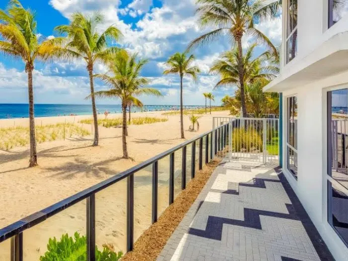 a walkway with palm trees and a body of water in the background