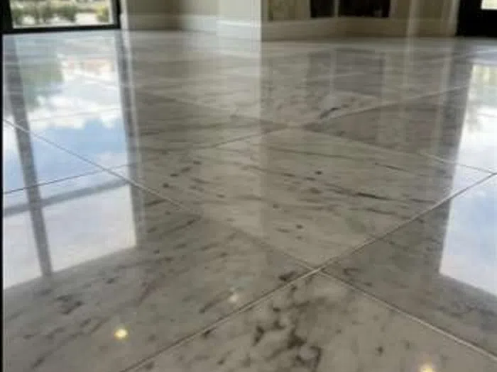 Shiny, polished marble floor tiles reflecting natural light and room interior after cleaning.