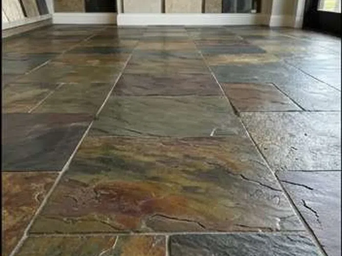 Close-up of restored slate flooring with natural multicolored stone tiles and visible texture in indoor setting.