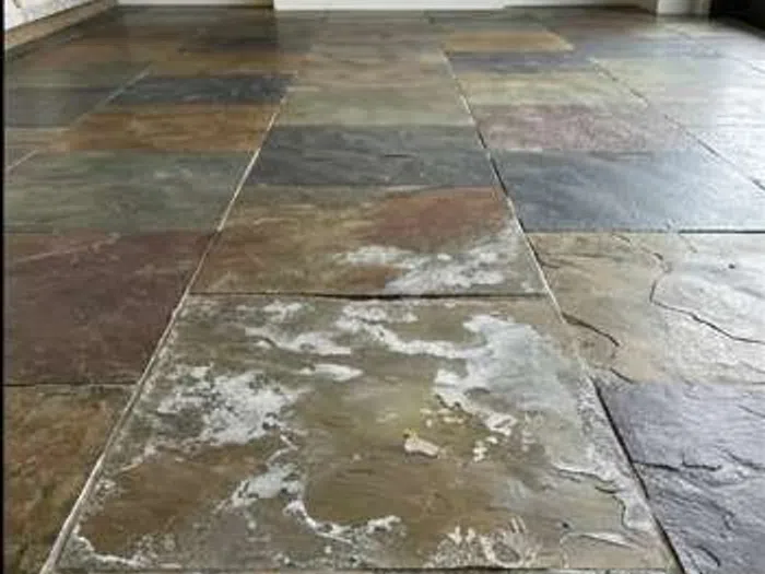 Close-up of slate floor with visible wear and discoloration before cleaning or restoration.