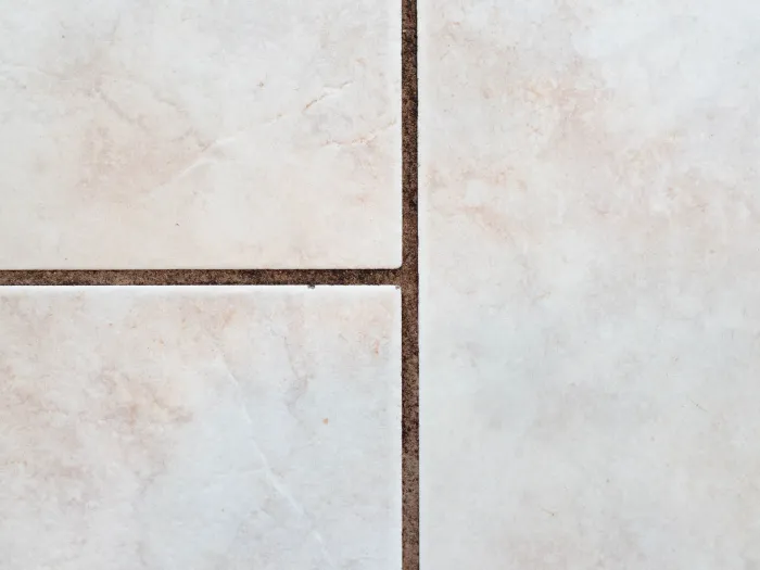 a close-up of a dirty dark grout line on a tile floor