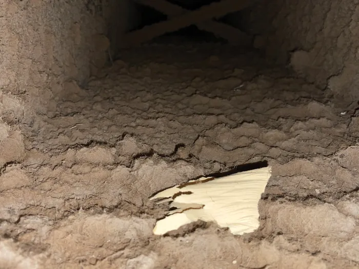 inside closeup shot of wood HVAC system with a pile of dirt and debris, looking like sludge