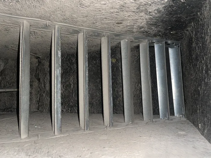 Inside of an HVAC system with metal dividers, covered with dirty dust, debris, and particles