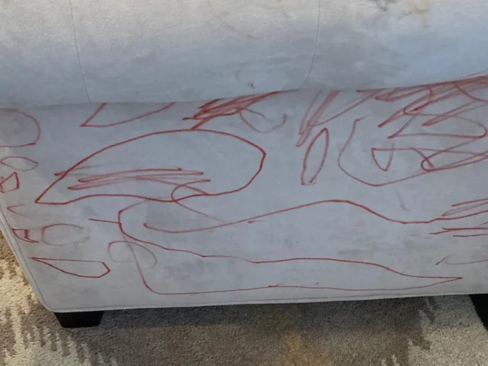 close up of the side of a microfiber couch with red marker drawings all over it