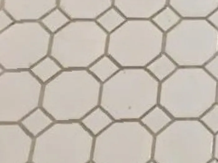 close up of octagon white floor tiles with diamonds in the corner with dirty grout lines before cleaning