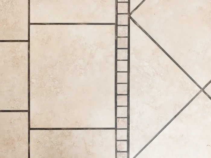 close up, top down view of a beige tile floor with dark dirty grout