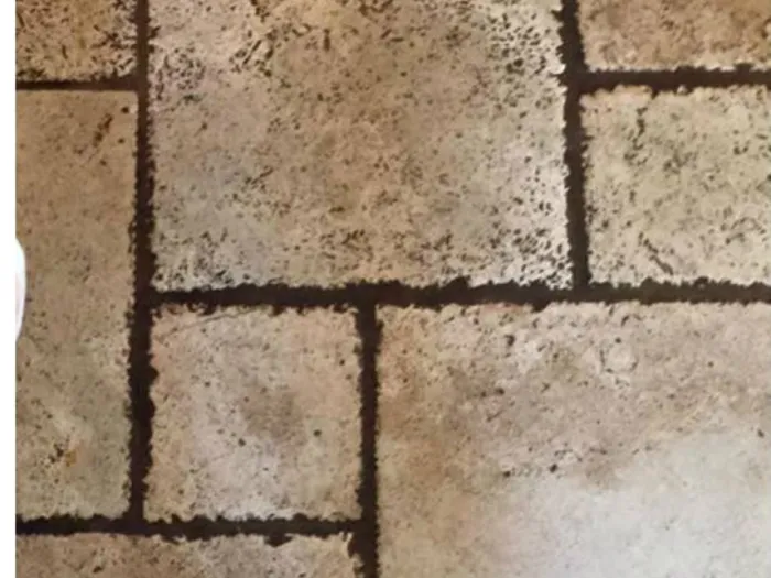 a person's shoes in shoe covers standing on a dirty tile floor with dark grout lines