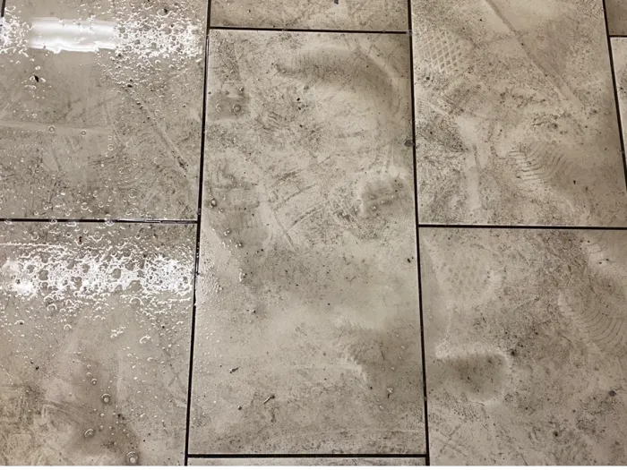 a group of grey tiles, wet and dirty after spraying with pretreatment before a professional cleaning