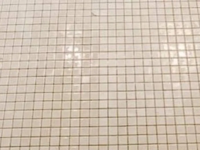 a bathroom with small square tiles and dark grout lines