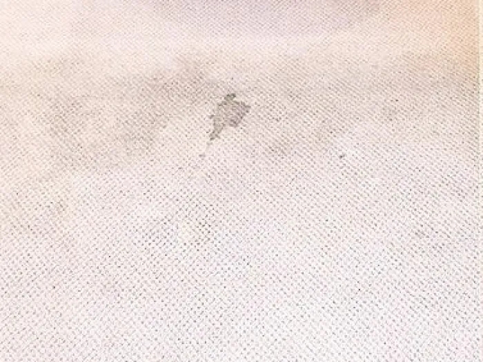 a wooden table on a white carpet with some visible gray stains