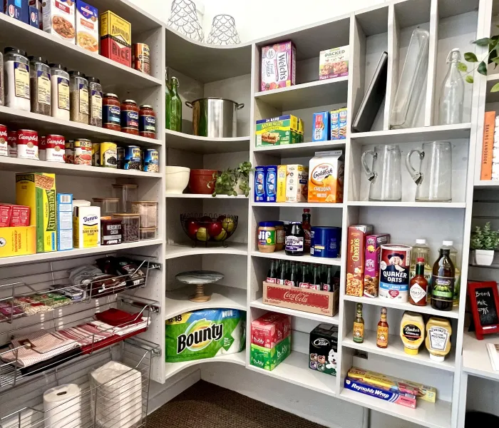 Custom kitchen pantry shelves stocked with canned goods, snacks, paper towels and beverages.