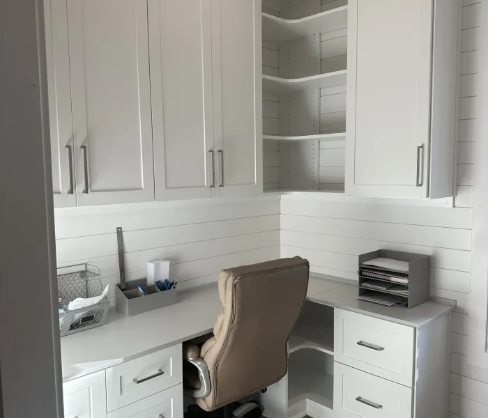 home office corner with white built-in cabinets, white drawers, white shelves and a beige ergonomic swivel chair
