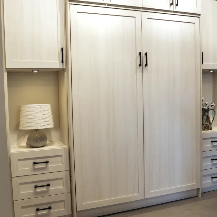 Murphy bed or wall bed folded up with wooden built-in cabinetry featuring nightstands and built-in cabinets.