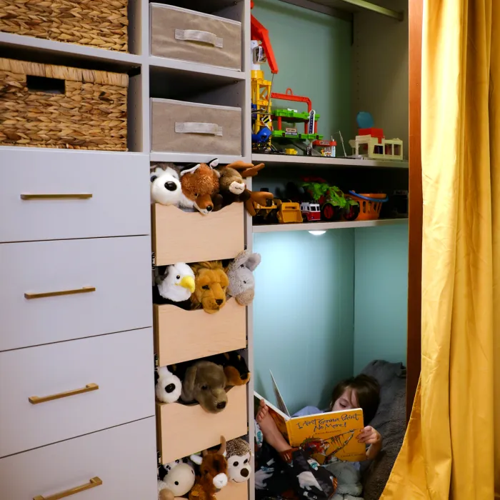 a child reading a book in a room with shelves and a basket