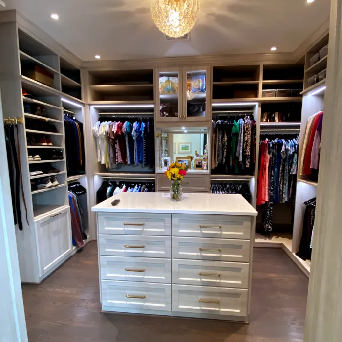 a room with a white cabinet and a white counter with a vase of flowers on it