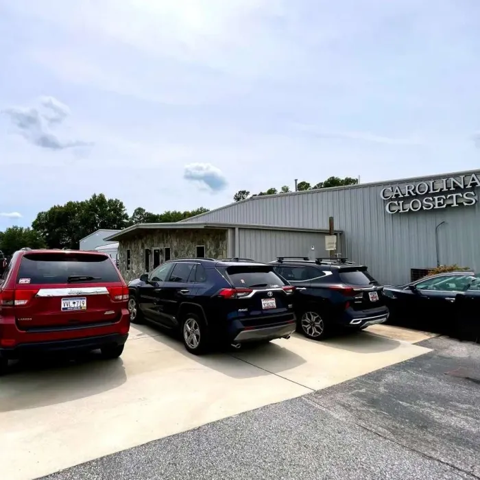 Parking lot of Carolina Closets showroom with multiple cars parked under a bright, partly cloudy sky.