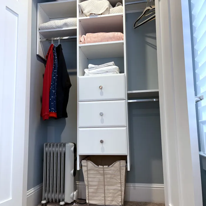 a closet with a shelf and a bed