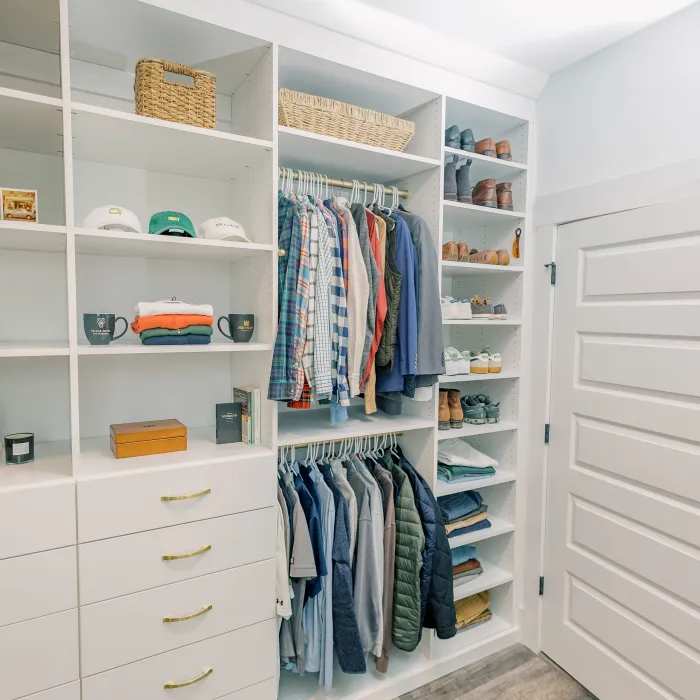 a closet with a white door and shelves with clothes