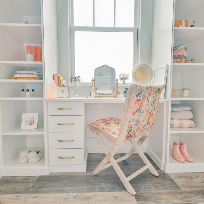 a white closet with a chair and a shelf with objects on it