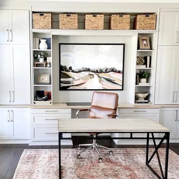 a room with white cabinets and a table with a chair and a painting on it