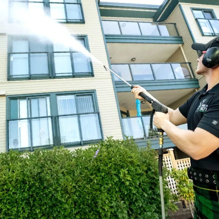 a man wearing a kilt and pressure washing a building