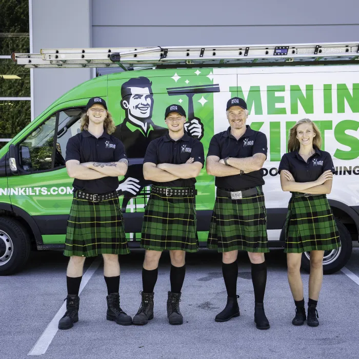 a group of people in kilts standing in front of a green van