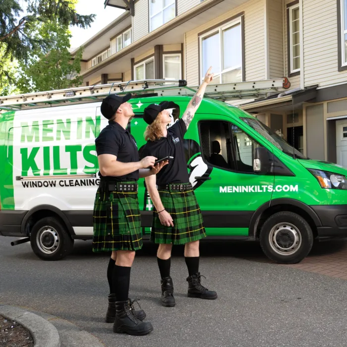 a group of people in kilts standing in front of a green van