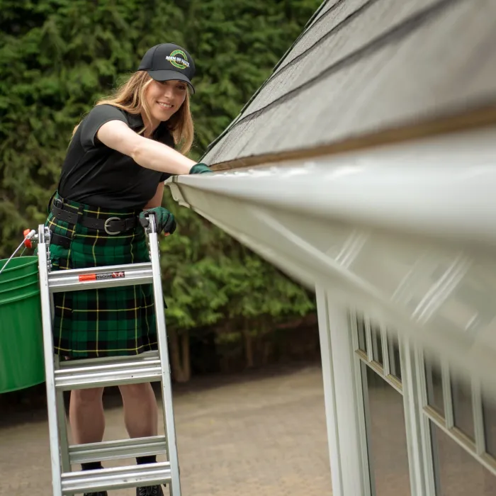 a woman cleaning a gutter