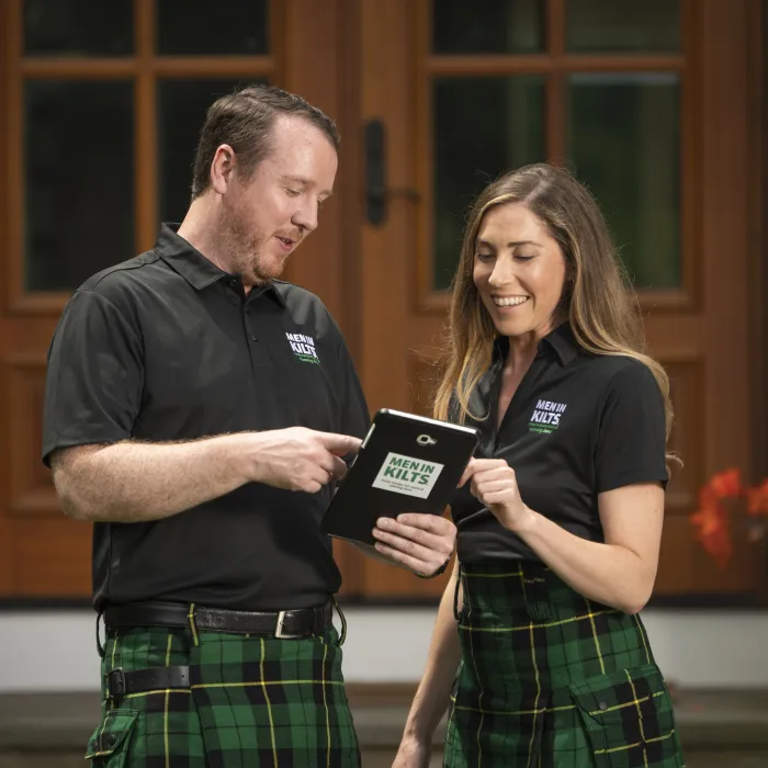 two people in front of a house looking at a tablet