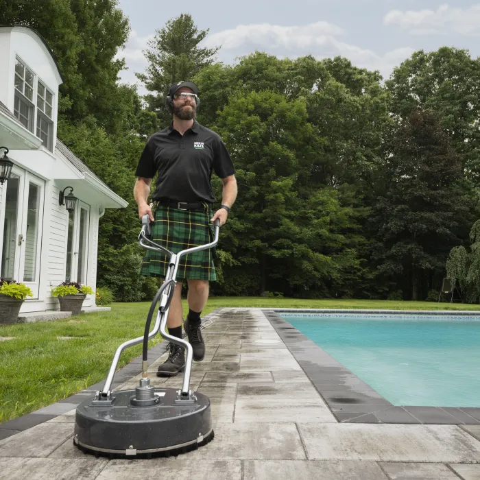 a man in a kilt washing a pool deck