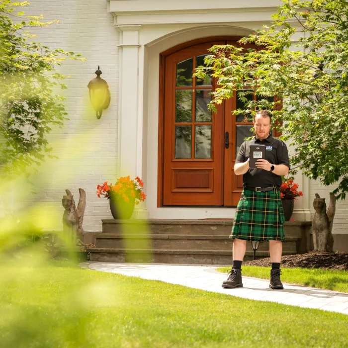 a person in a kilt standing outside a house