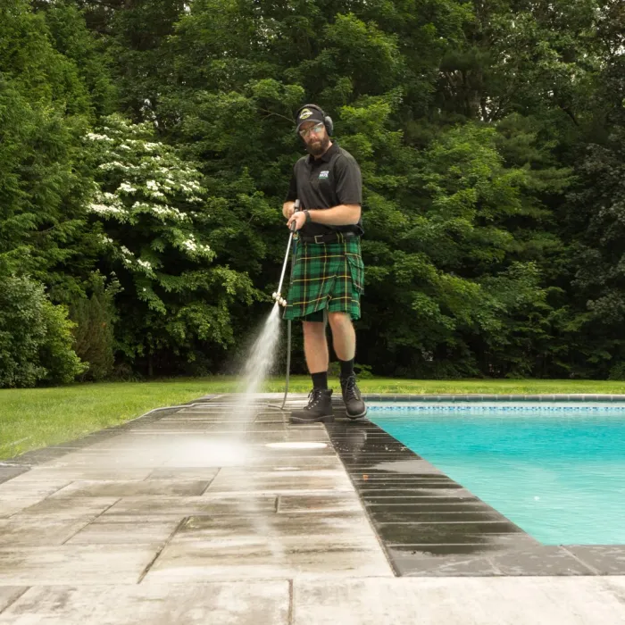 a man pressure washing around a pool