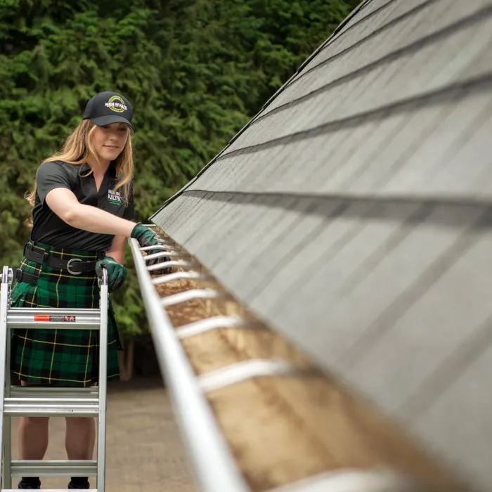 a person cleaning gutters on a ladder