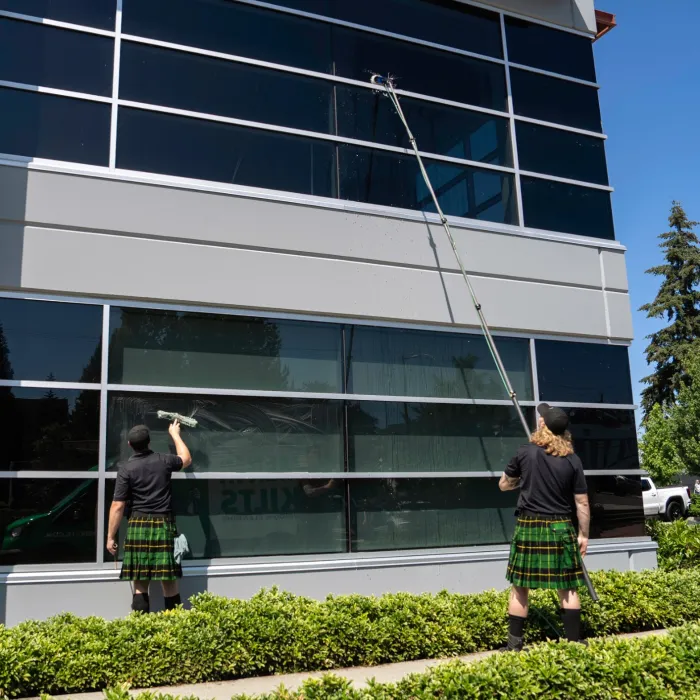 two people in kilts washing windows