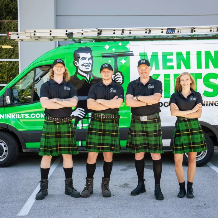 a group of people in kilts standing in front of a van