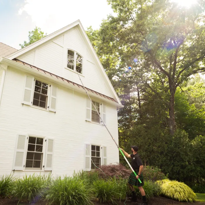 a person standing in front of a house cleaning a window