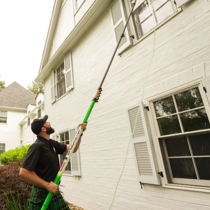 a man holding a broom outside a house