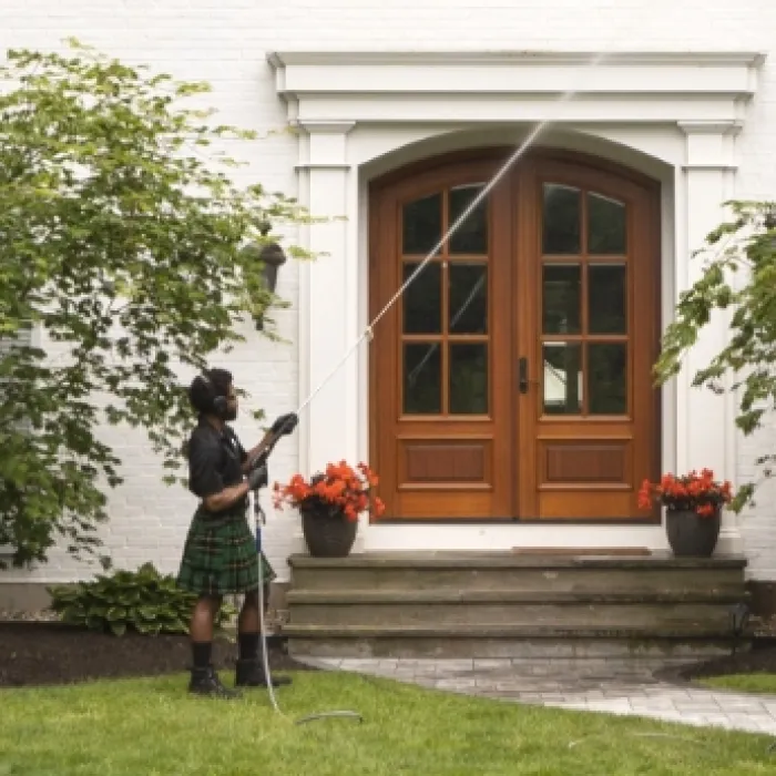 a person in a kilt holding a cane in front of a house