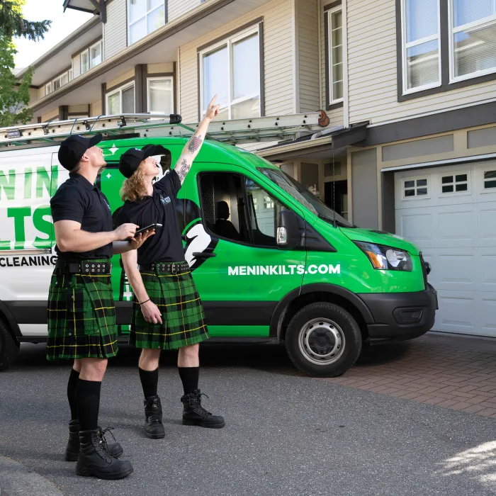 two people in kilts standing in front of a green van