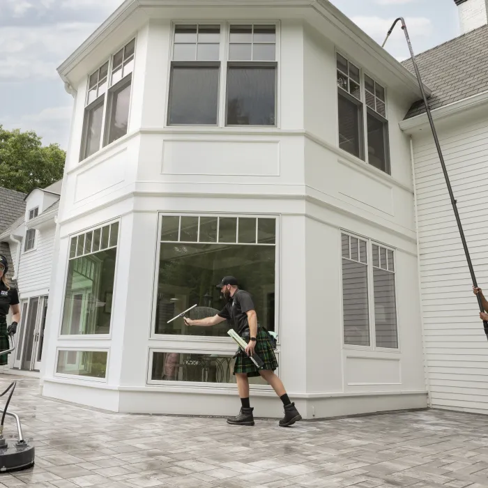 a group of people in kilts cleaning the outside of a house