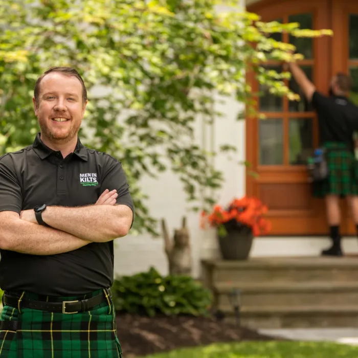 A man standing in front of a house with his arms crossed