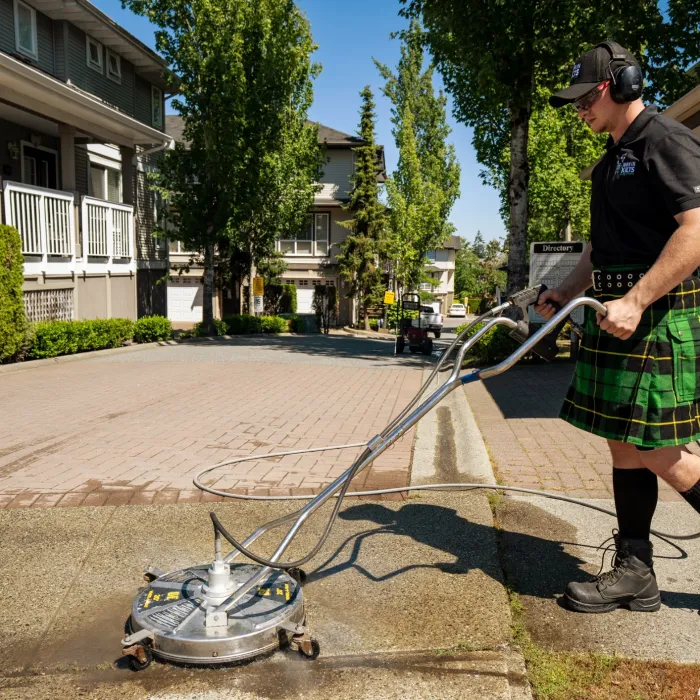 a man wearing a kilt and using a surface washer