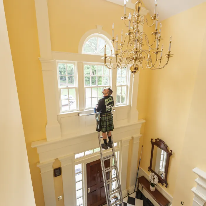 a person standing on a ladder in a room with a chandelier