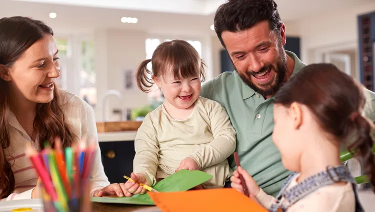 Happy family with father, mother, and two daughters doing arts and crafts together at home.