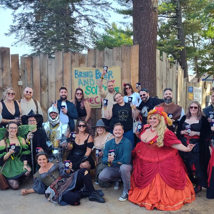 Group of people in medieval and fantasy costumes holding drinks at an outdoor festival on a sunny day