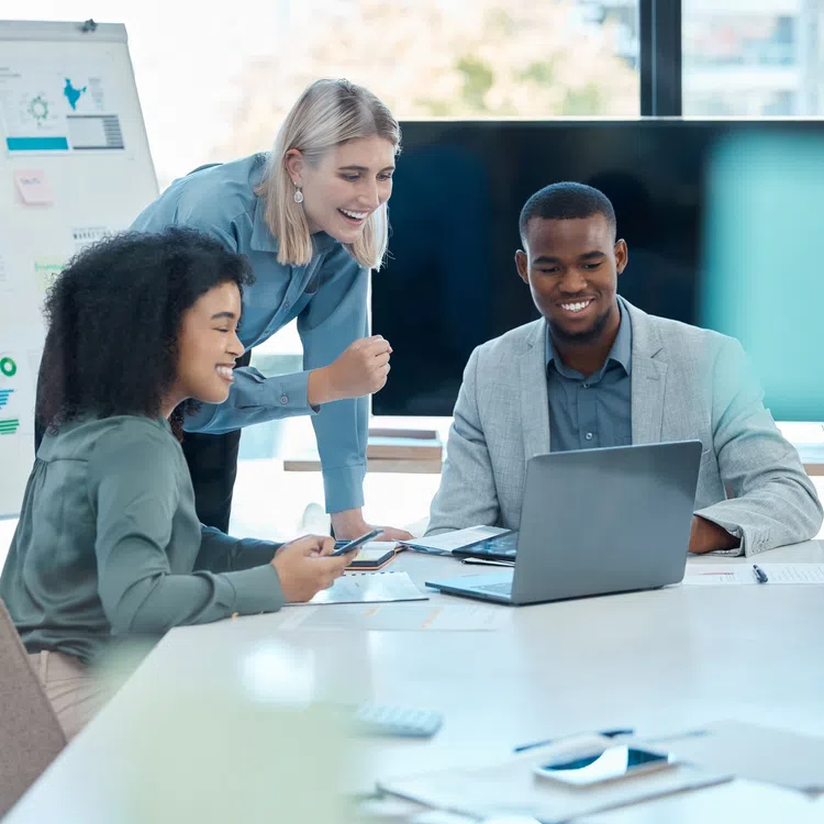 Diverse business team collaborating on a project with laptop and documents in a bright modern office.