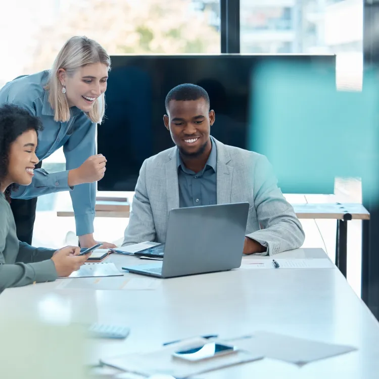 Diverse business team collaborating on a project with laptop and documents in a bright modern office.