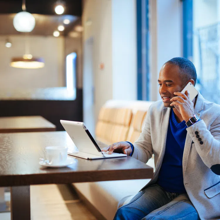 a person sitting at a table with a laptop and a phone