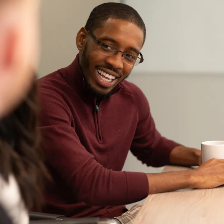Smiling man in a meeting enjoying conversation with colleagues at a modern table