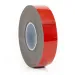 Roll of black foam tape with red adhesive backing on a white background close-up